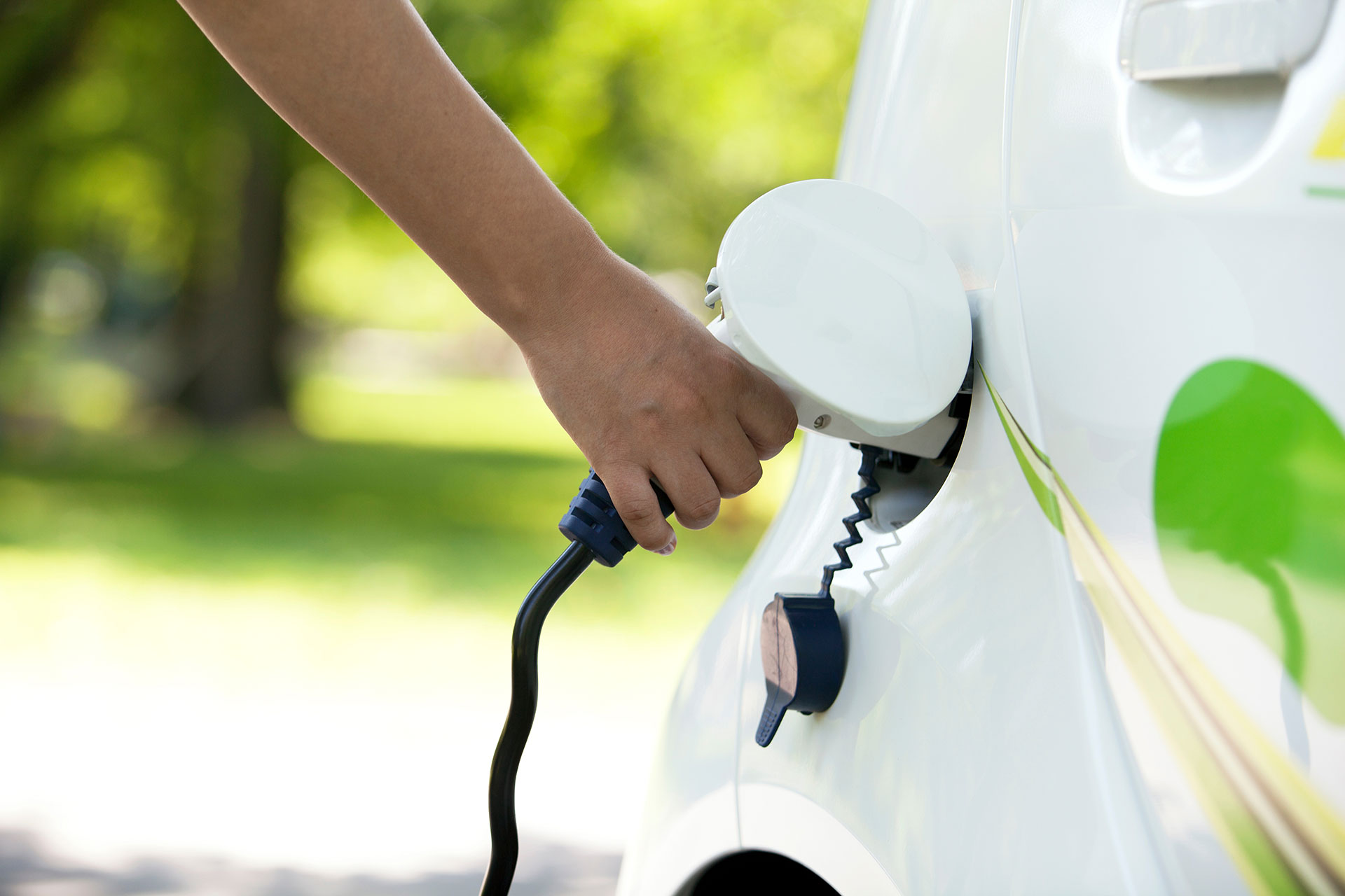 hand of person charging white electric car